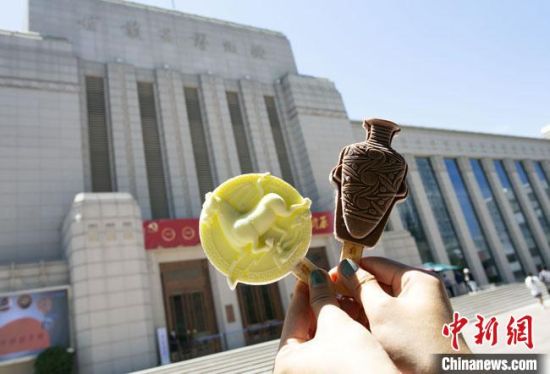 2021年7月30日，游客手拿“銅奔馬”“彩陶瓶”造型的雪糕，在甘肅省博物館前拍照打卡?！「哒?攝