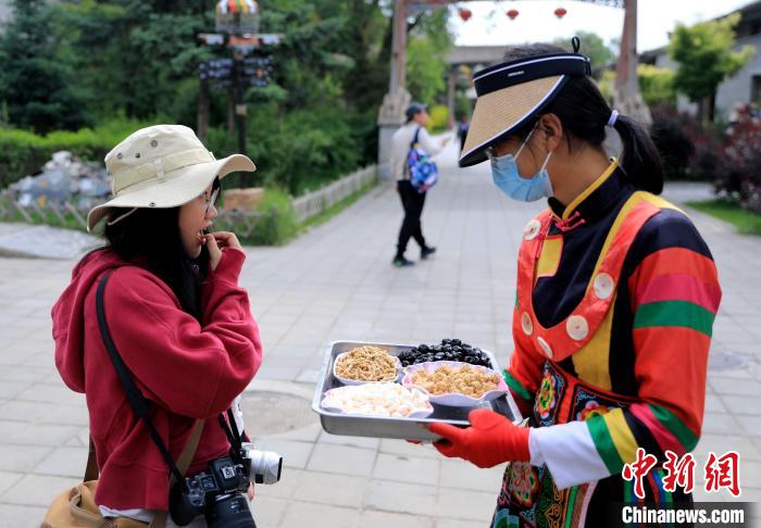 圖為身穿土族服飾的女性介紹當(dāng)?shù)靥厣〕??！⊙Φ?攝