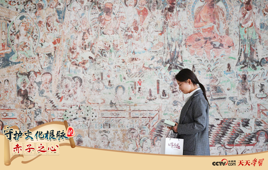 2023年4月25日，敦煌研究院文物數(shù)字化保護團隊創(chuàng)意營銷人員廖雪婷從一幅高保真復制壁畫前走過。