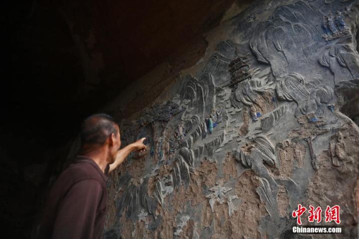 7月15日，甘肅省平?jīng)鍪袥艽h百里石窟長廊羅漢洞石窟內(nèi)，該窟文保員郭建平介紹窟內(nèi)石刻彩繪壁畫。郭建平家中三代人曾自發(fā)保護羅漢洞石窟。羅漢洞石窟遺存40余個窟龕，以北魏至清代風(fēng)格為主。中新社記者 李亞龍 攝