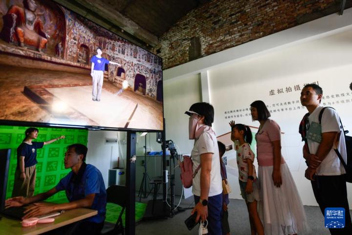 7月22日，游客體驗“尋境敦煌——數(shù)字敦煌沉浸展”后，在虛擬演播廳拍攝一段真人與洞窟虛擬場景交互的視頻。新華社記者 郎兵兵 攝</p>
<p>
