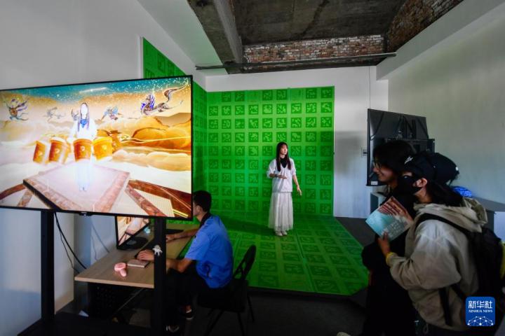 7月22日，游客體驗“尋境敦煌——數(shù)字敦煌沉浸展”后，在虛擬演播廳拍攝一段真人與洞窟虛擬場景交互的視頻。新華社記者 郎兵兵 攝</p>
<p>